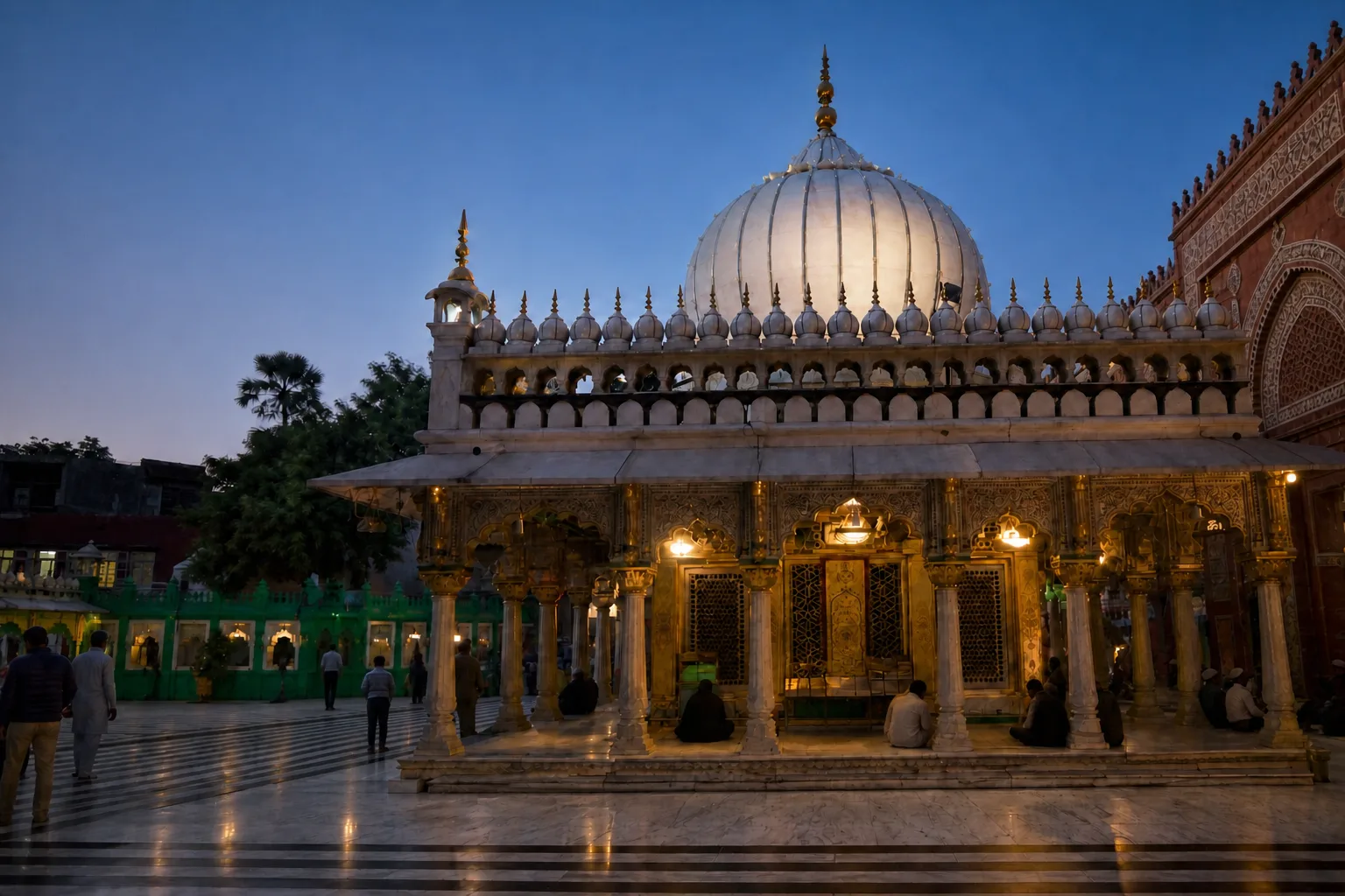 White-domed shrine and illuminated arcade reflected on a polished courtyard at dusk